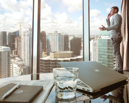 A modern corporate professional standing up at a desk near a window overlooking Monterrey city layout